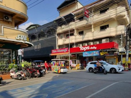 Tops Daily und weitere Geschäfte an einer Straße in Pattaya mit Rollern und Autos