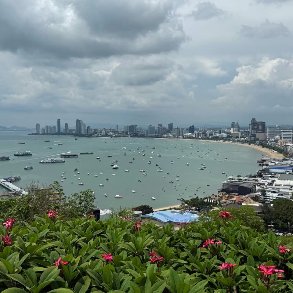 Aussicht auf die Bucht von Pattaya mit Meer, Booten, Küstenlinie und Stadtansicht unter bewölktem Himmel