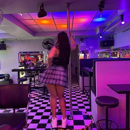 Bar in Pattaya bei Nacht mit Tänzerin, buntem Licht und Sitzbereich