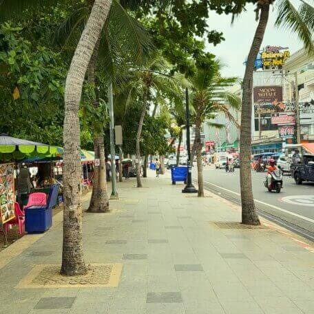 Strandpromenade an der Beach Road in Pattaya mit Palmen und kleinen Ständen