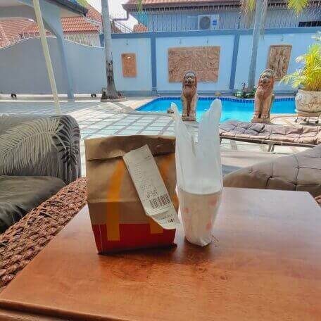 McDonald’s Bestellung mit Tüte und Getränk auf einem Tisch neben einem Pool