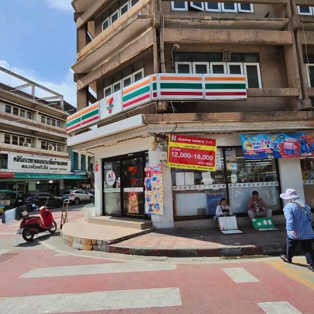 7-Eleven im Alltag von Pattaya 7-Eleven Filiale an einer Straße in Pattaya mit Rollern und Passanten