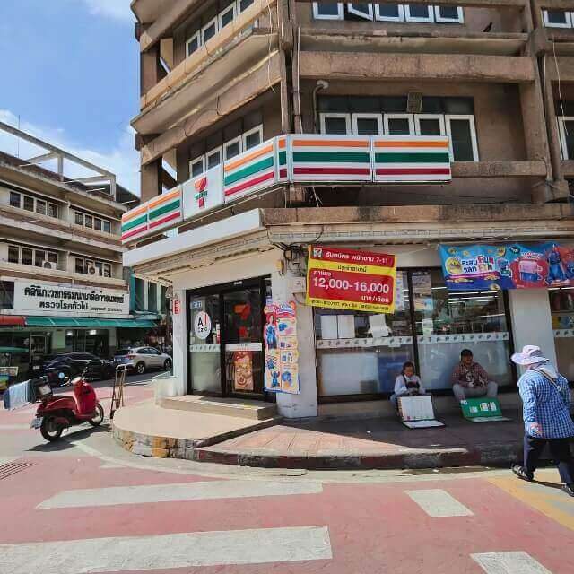 7-Eleven Filiale an einer Straße in Pattaya mit Rollern und Passanten