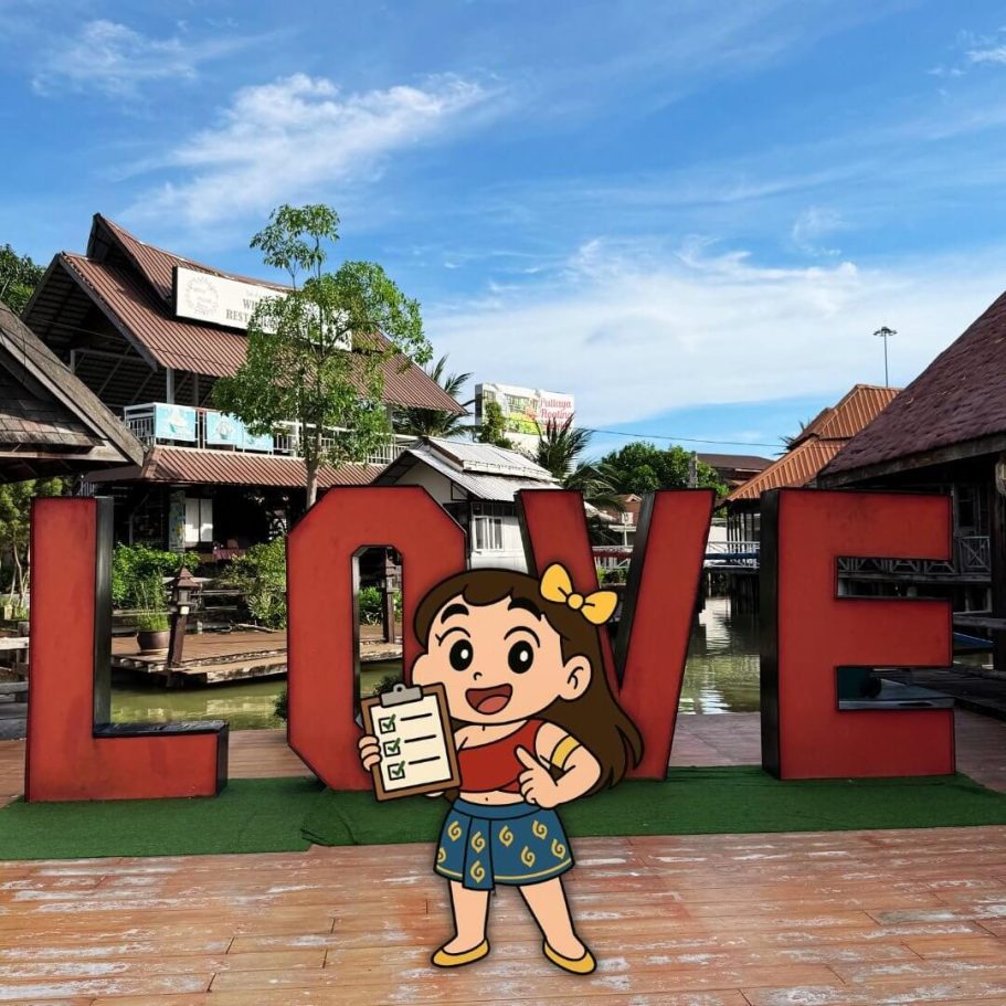 LOVE-Schriftzug am Eingang des Pattaya Floating Market mit gezeichneter Figur und Holzgebäuden im Hintergrund