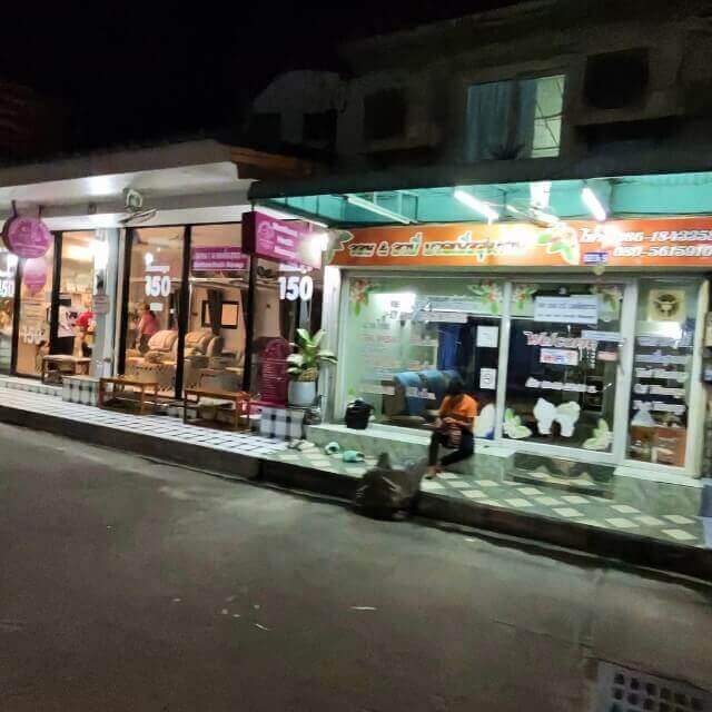 Massagesalons in Pattaya am Abend, teilweise bereits beim Schließen, mit beleuchteten Eingängen und Preisschildern