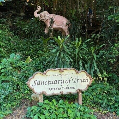 Sanctuary of Truth Schild in Pattaya, Thailand Schild mit der Aufschrift Sanctuary of Truth Pattaya Thailand zwischen dichter Bepflanzung und Elefantenfigur