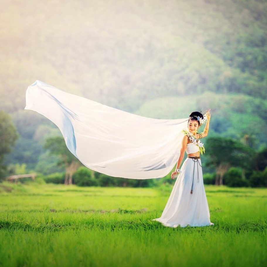 Braut in weißem Hochzeitskleid mit Schleier in Pattaya, Thailand, inmitten grüner Natur Eine Frau in einem traditionellen weißen Hochzeitskleid mit langem Schleier in Pattaya, Thailand, umgeben von grüner Natur.