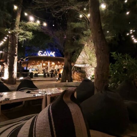 Cave Beach Club in Na Jomtien mit beleuchtetem Außenbereich, Bäumen und gemütlichen Sitzplätzen