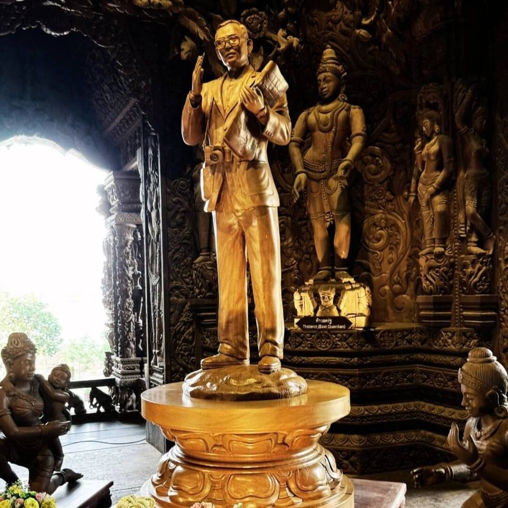 Statue von Lek Viriyaphan im Inneren des Sanctuary of Truth in Pattaya, umgeben von detaillierten, mythologischen Holzschnitzereien.