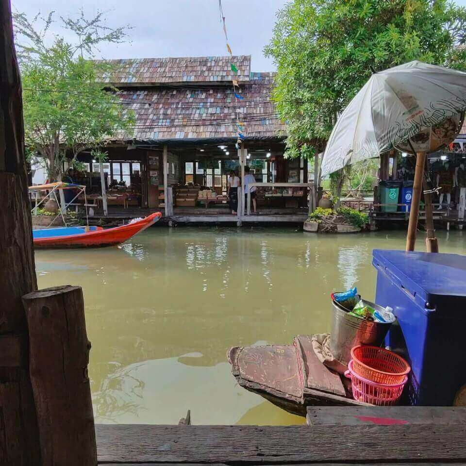 Holzgebäude, Wasserweg und Boot direkt vor den Marktständen am schwimmenden Markt in Pattaya