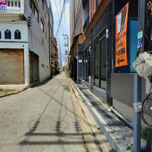 Schmale Seitenstraße in Jomtien mit Gebäuden, Stromleitungen und Zufahrt zu einer Nebenstraße