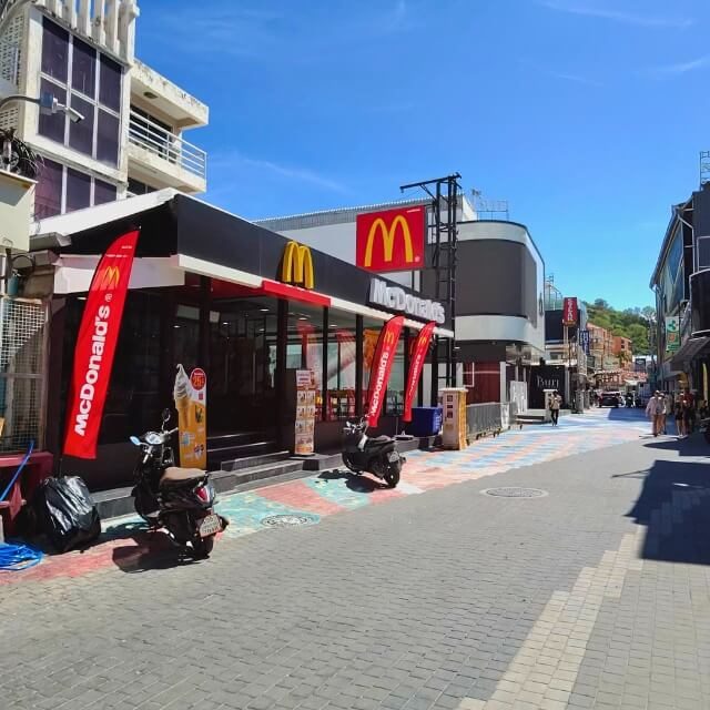 Walking Street in Pattaya bei Tag mit McDonald’s, Motorrollern und Fußgängern