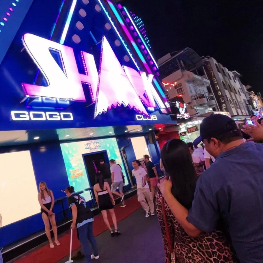 Eingang des Shark GoGo Clubs in der Walking Street mit leuchtendem blau-pinkem Neonschild, Hostessen und Besuchern im Nachtleben von Pattaya