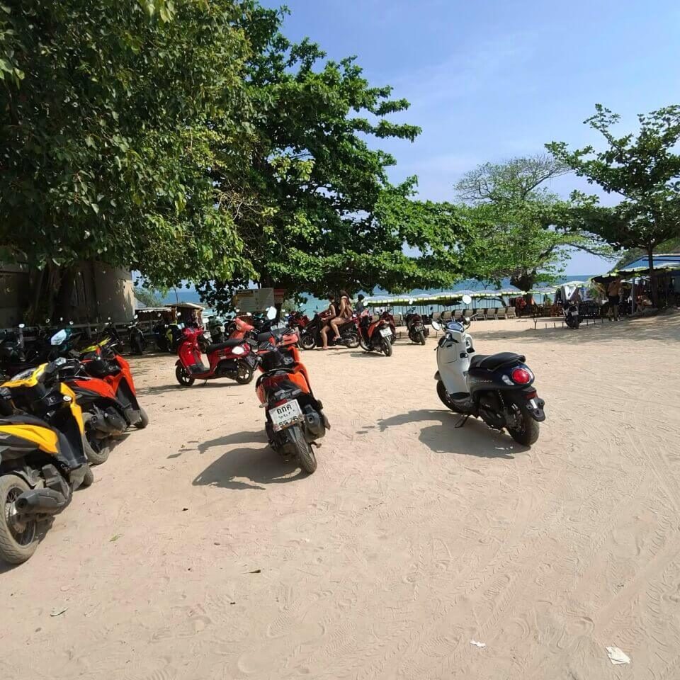 Scooter auf Koh Larn am Strand Mehrere geparkte Scooter auf Koh Larn nahe dem Strand unter Bäumen