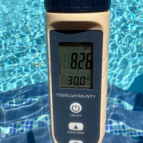 Wasserwerte mit digitalem Testgerät prüfen Digitales Wassertestgerät mit pH-Wert 8,26 und 30 °C vor einem Pool