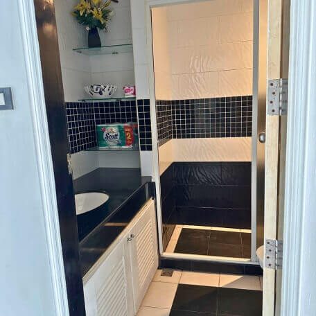 Badezimmer mit Dusche, Waschbecken und Hygieneartikeln