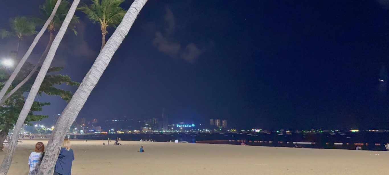 Pattaya Beach bei Nacht Pattaya Beach bei Nacht mit Palmen, Strand und beleuchtetem Pattaya City Sign im Hintergrund