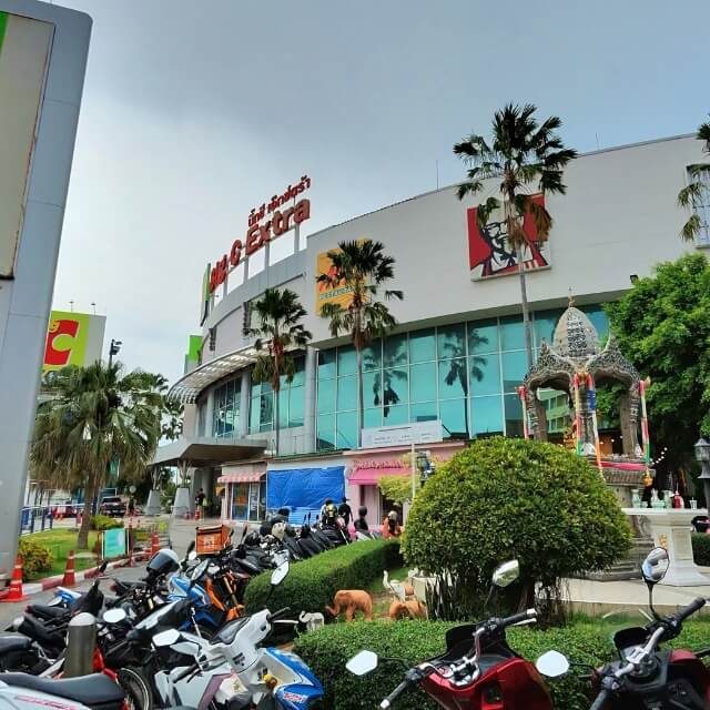 Big C Extra Einkaufszentrum mit Glasfassade, Palmen, Motorrädern und Außenbereich unter blauem Himmel