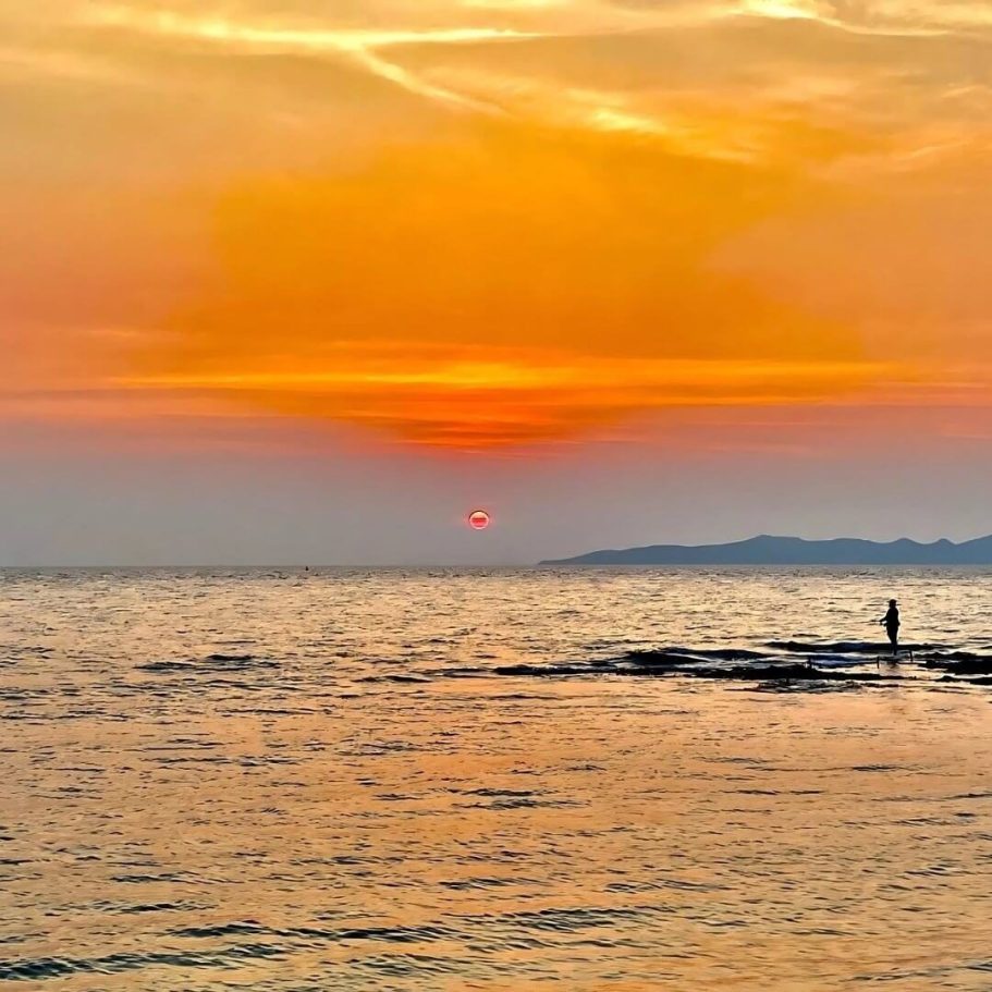 Sonnenuntergang am Strand von Pattaya mit orangefarbenem Himmel und einsamer Silhouette während der COVID-Zeit