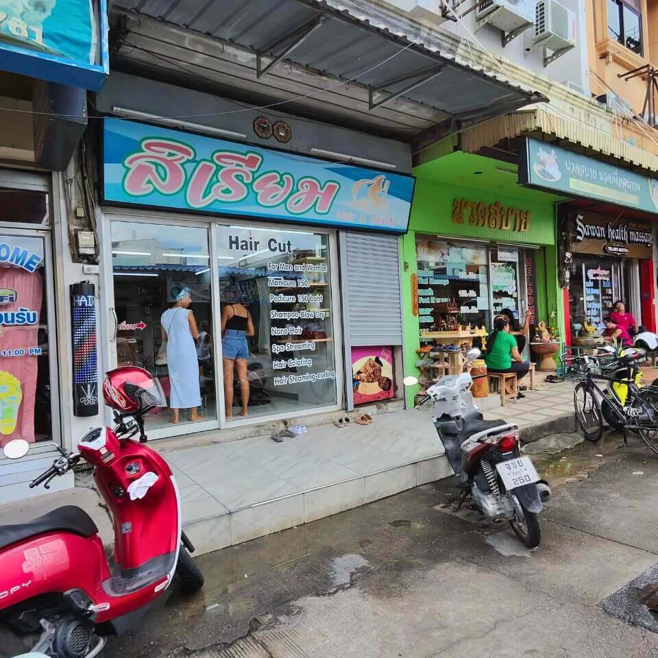 Mehrere kleine Geschäfte und Massagesalons an einer Straße in Pattaya mit Rollern vor den Eingängen