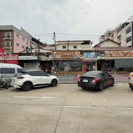 Straßenansicht in Pattaya mit mehreren Massagegeschäften und Fahrzeugen davor