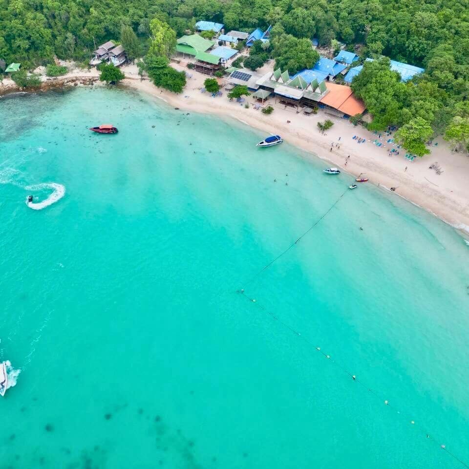 Tropische Küste in Thailand Luftaufnahme eines tropischen Strandes mit türkisfarbenem Wasser, Booten und Gebäuden am Ufer
