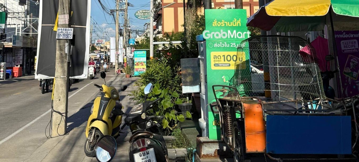 GrabMart Schild vor einem Geschäft mit geparkten Rollern an einer Straße in Pattaya