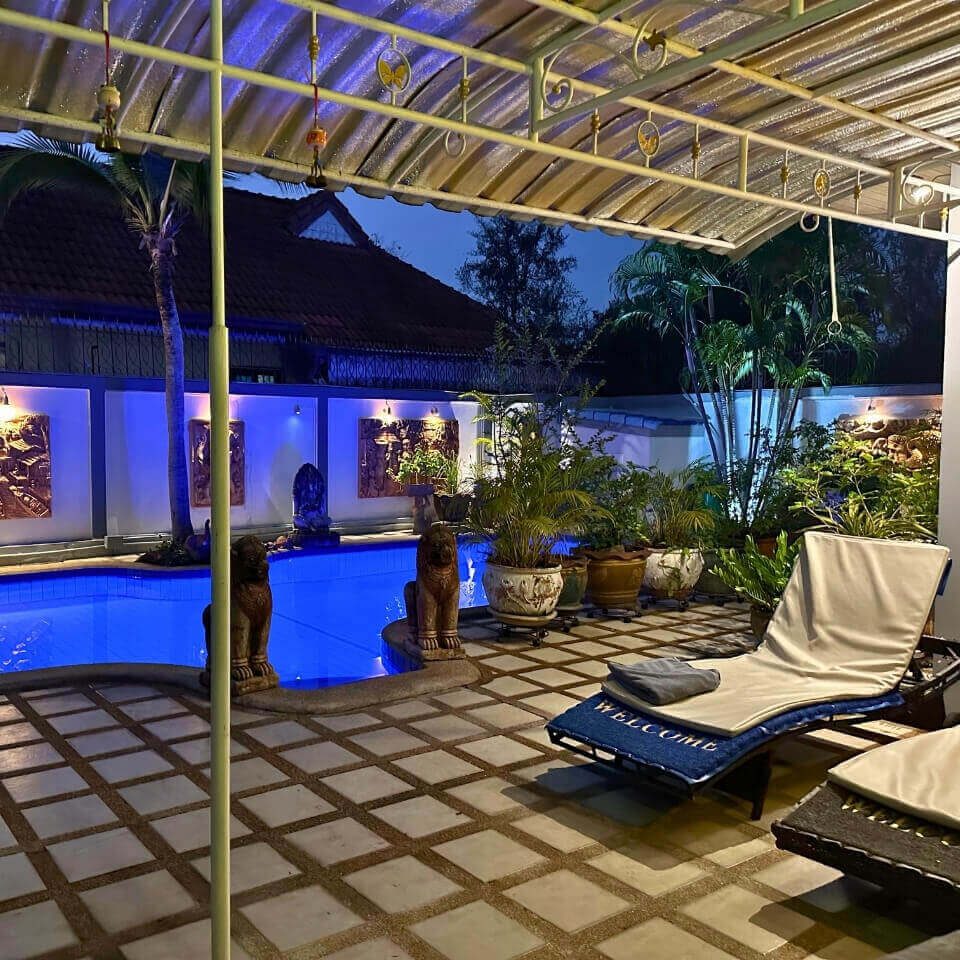 Beleuchteter Poolbereich einer Unterkunft in Pattaya mit Liegen, Pflanzen und überdachter Terrasse