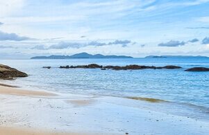 Ruhiger Küstenabschnitt bei Wong Amat Wong Amat Beach mit ruhigem Meer, Sandstrand und Felsen vor der Küste