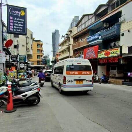 Rettungsfahrzeug im Straßenverkehr in Pattaya zwischen Motorrädern, Geschäften und Gebäuden