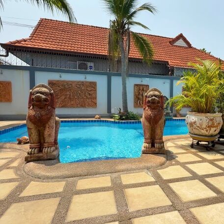 Privater Pool in Pattaya mit zwei Löwenstatuen, Palmen und abgeschirmtem Grundstück im Hintergrund