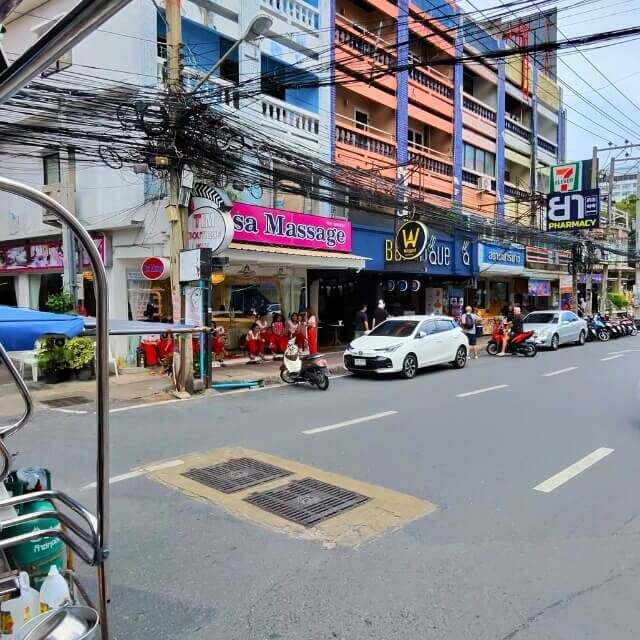 Massagesalons an einer Straße in Pattaya mit mehreren Geschäften und Fahrzeugen