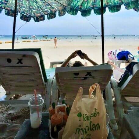 Strandtag auf Koh Larn Blick von Strandliegen auf das Meer von Koh Larn mit Getränken und Taschen im Vordergrund
