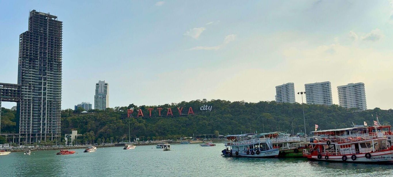 Pattaya Bay mit Booten, Hochhäusern und Pattaya City Schriftzug am Hang