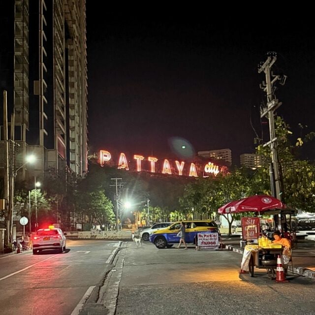 Straße bei Nacht mit beleuchtetem Pattaya City Schriftzug im Hintergrund